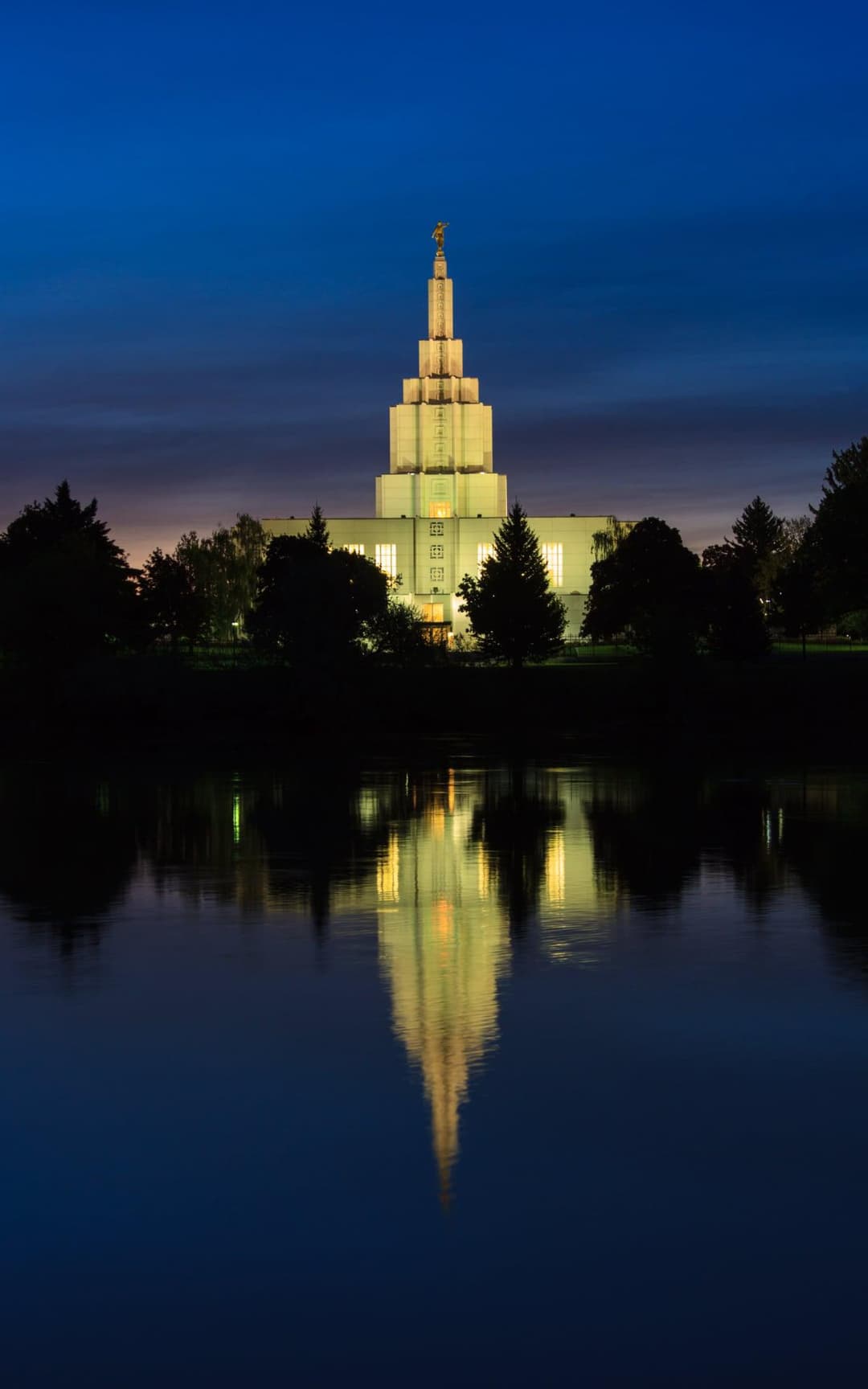 The temple spire casting a perfect reflection in the still river at night.