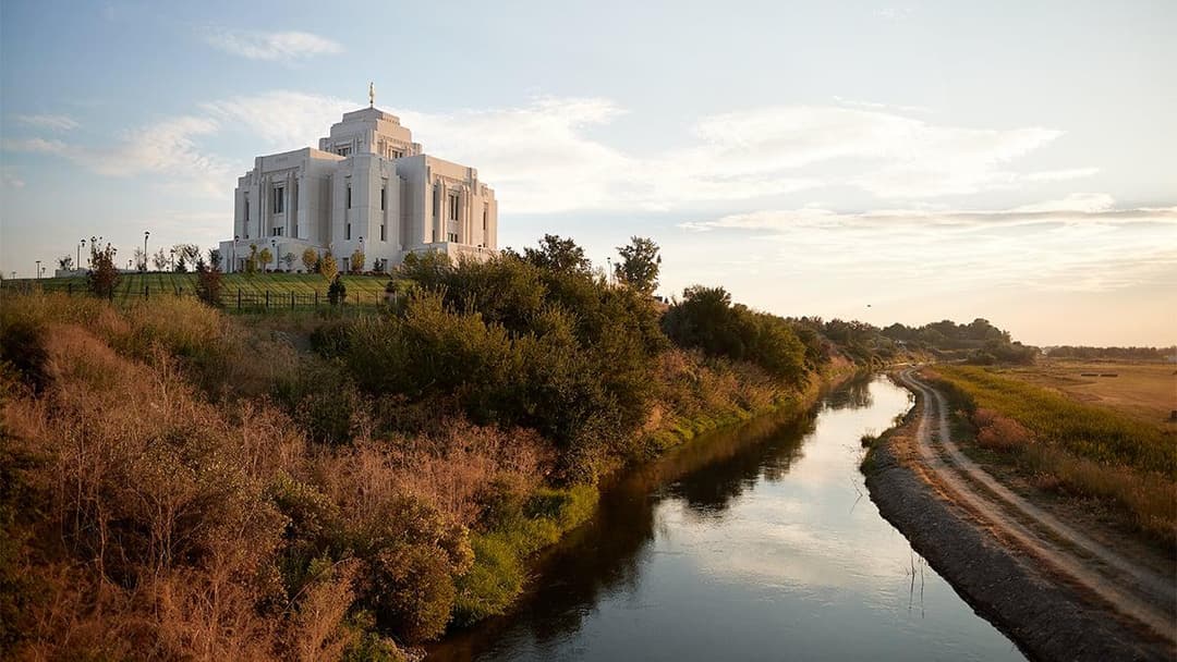 Meridian Idaho Temple at golden hour, overlooking a river and path.