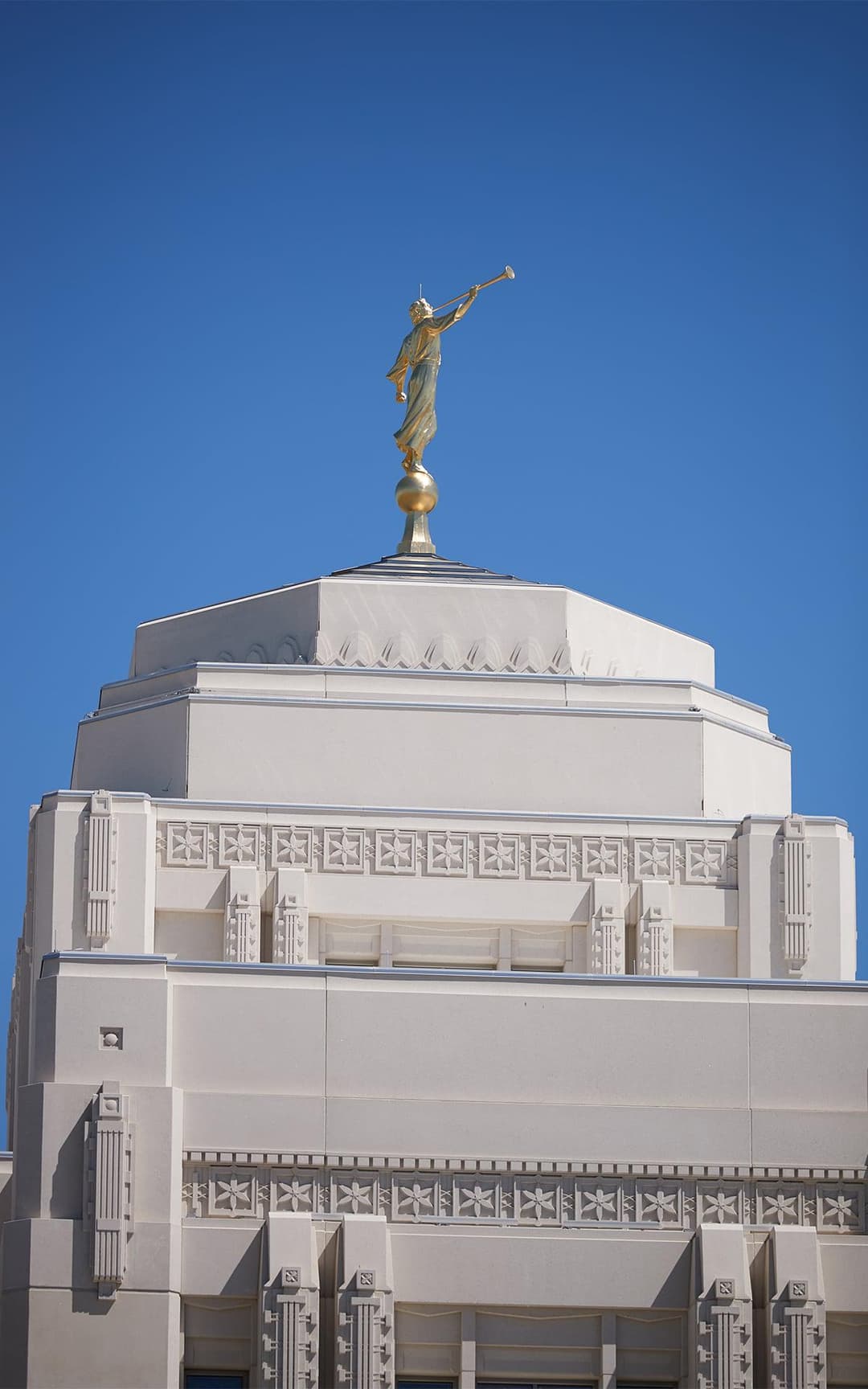 Golden Angel Moroni statue on Meridian Idaho Temple under clear blue sky.