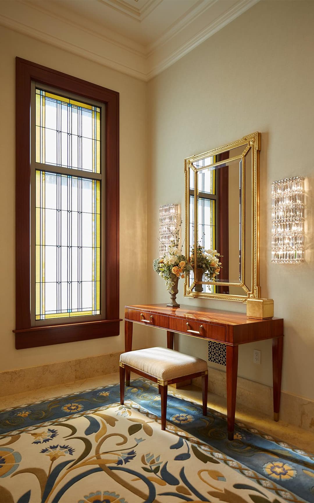 Interior: Stained glass window, console table with mirror, and patterned rug.