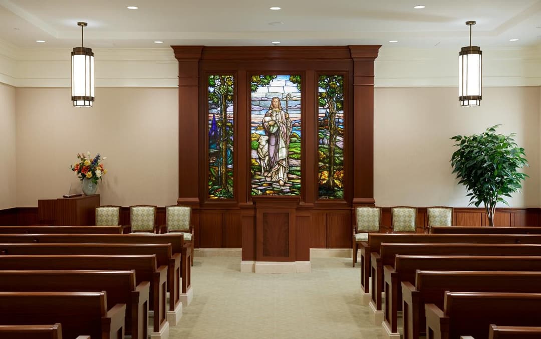 Chapel interior featuring pews and a stained-glass window of Christ.