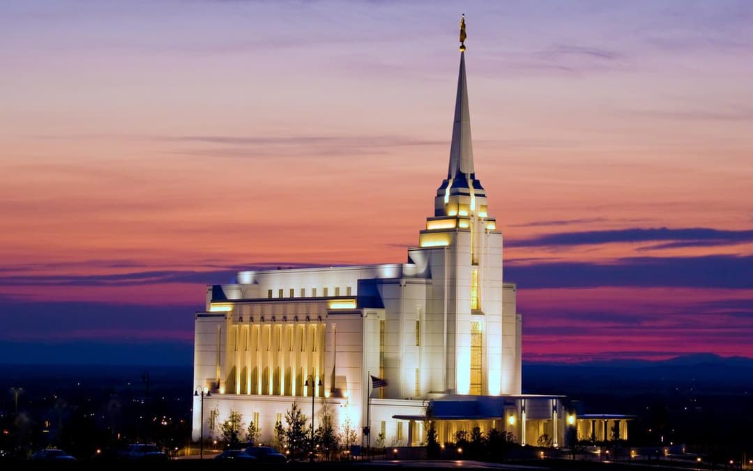 Rexburg Idaho Temple illuminated at twilight with spire and Angel Moroni.