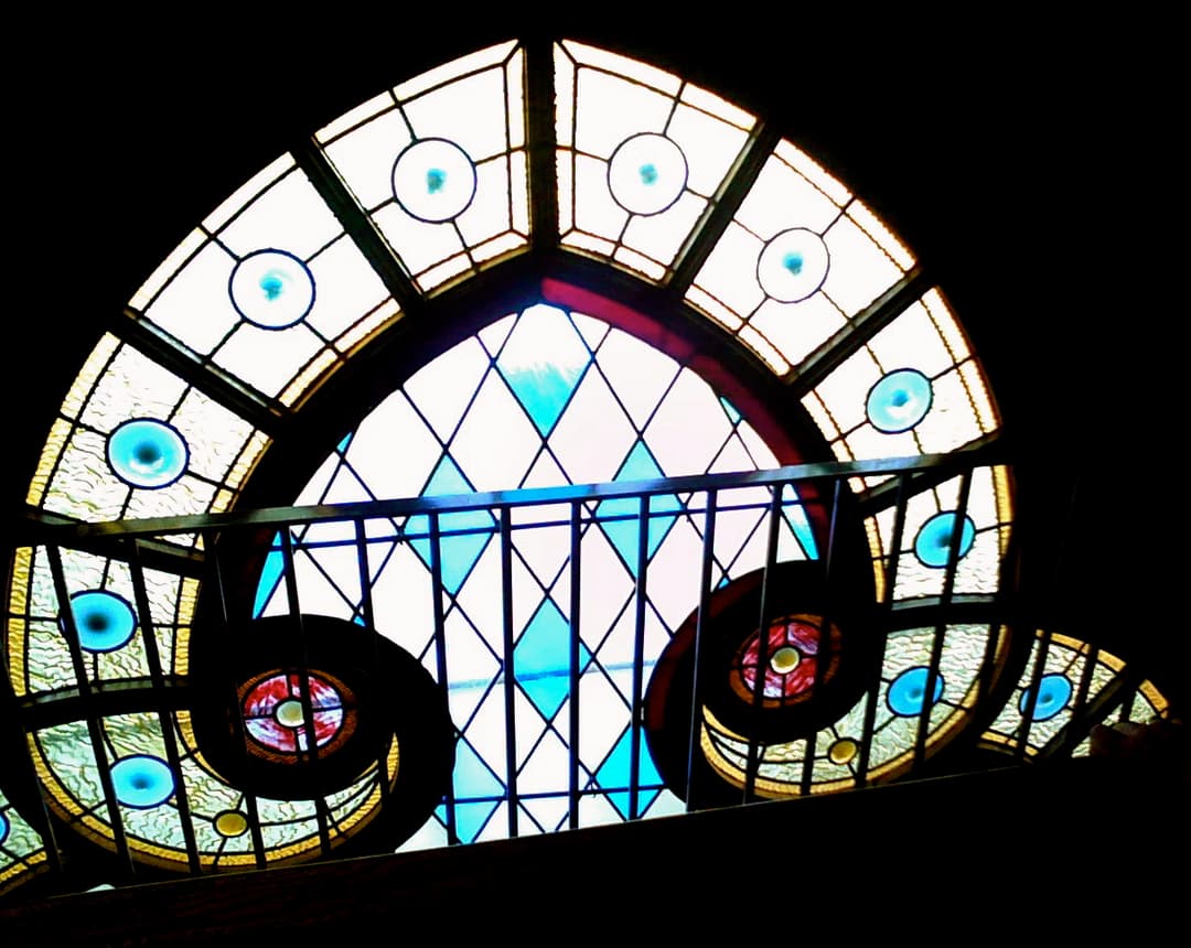 Detail of the stained glass window and interior balcony railing.