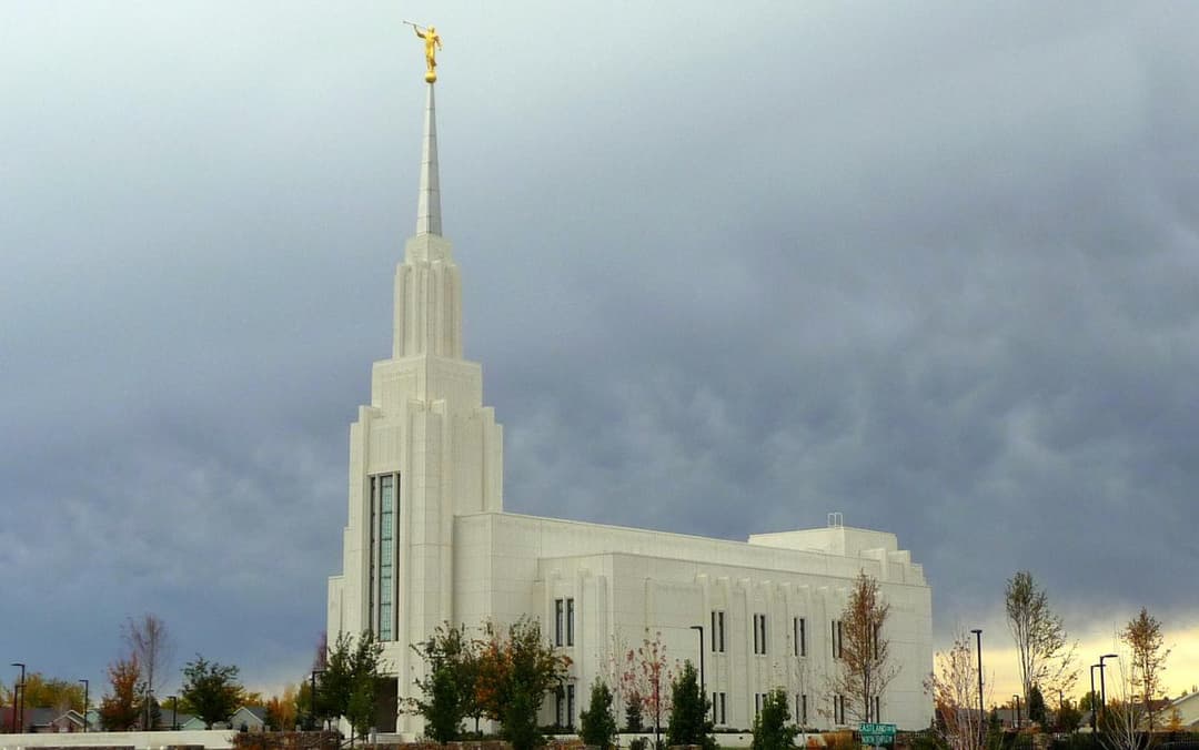 Exterior view of the Twin Falls Idaho Temple and spire under a stormy sky.