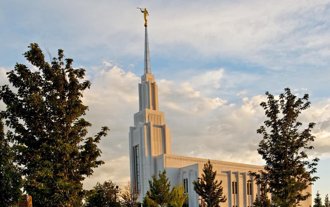 Twin Falls Idaho Temple spire framed by trees in late afternoon light.