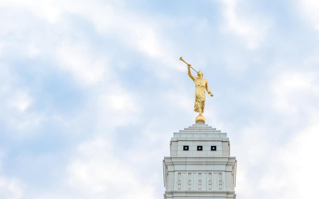 Golden Angel Moroni statue on Indianapolis Indiana Temple spire, cloudy sky.