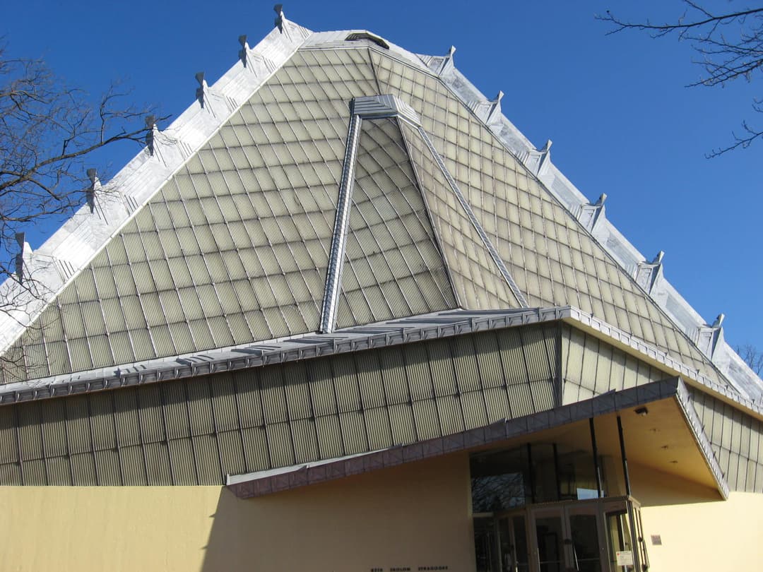 Low-angle exterior view of the pyramidal roof and main entrance.