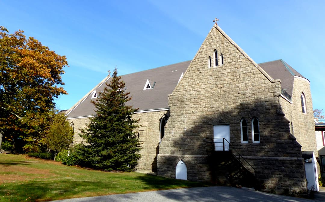 Exterior view of the stone church and grounds on a clear day