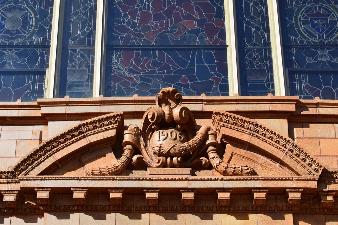 Carved 1906 pediment detail beneath stained glass windows