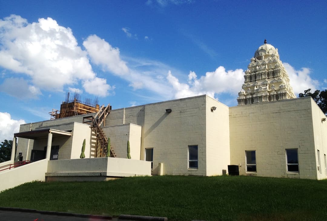 Exterior view of the temple featuring the ornate white vimana tower.