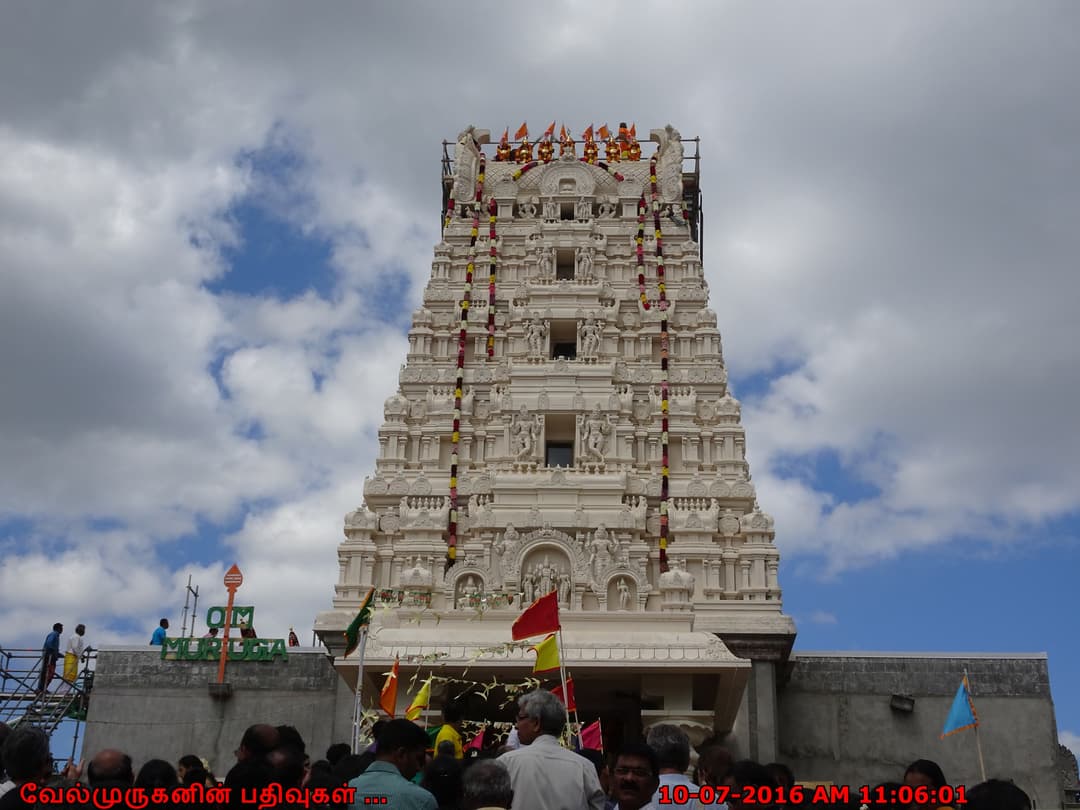 Low-angle view of the ornate white rajagopuram with crowds gathered below