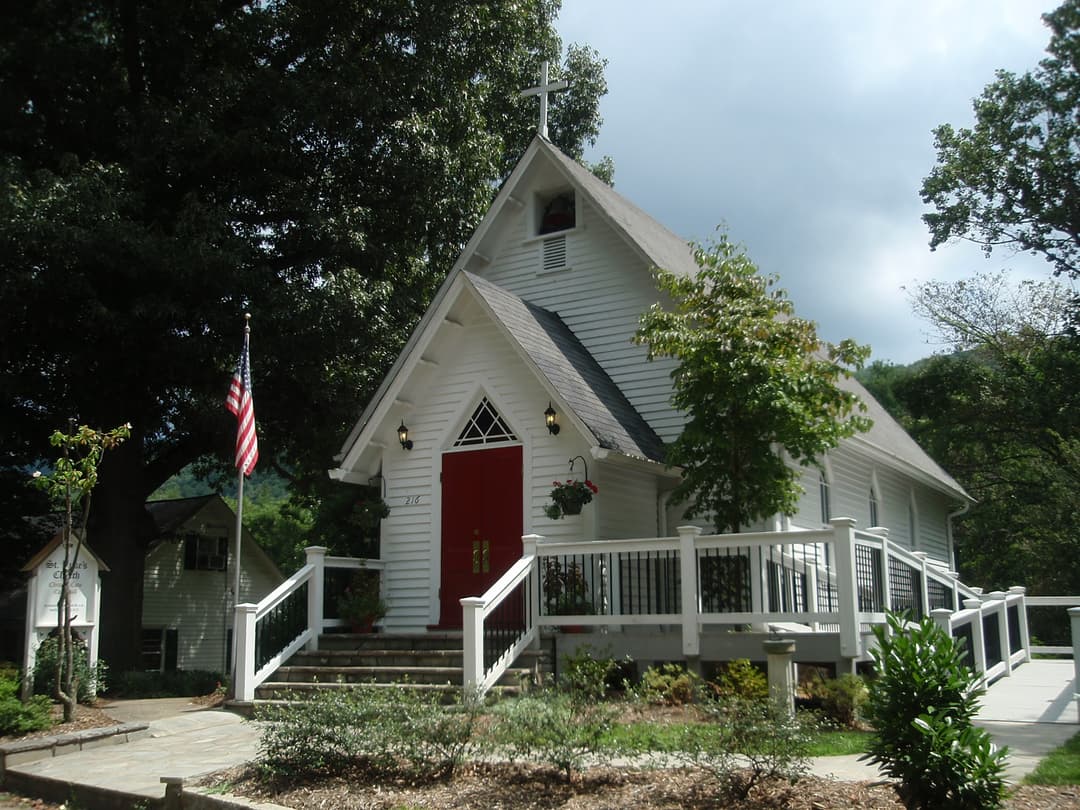 Exterior front view of the white wooden chapel with red doors