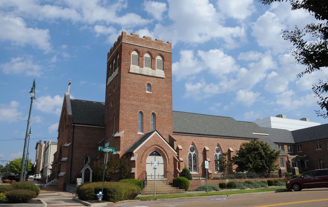 Exterior daytime view of the brick church and crenellated bell tower