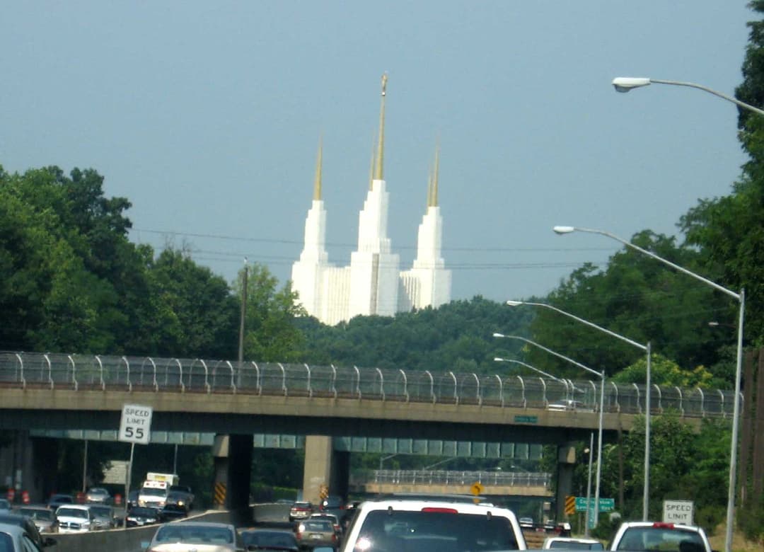Washington D.C. Temple's spires viewed from a busy highway.