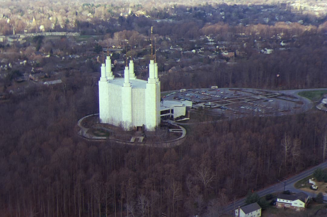 Aerial view of Washington D.C. Temple with six spires, surrounded by bare trees.