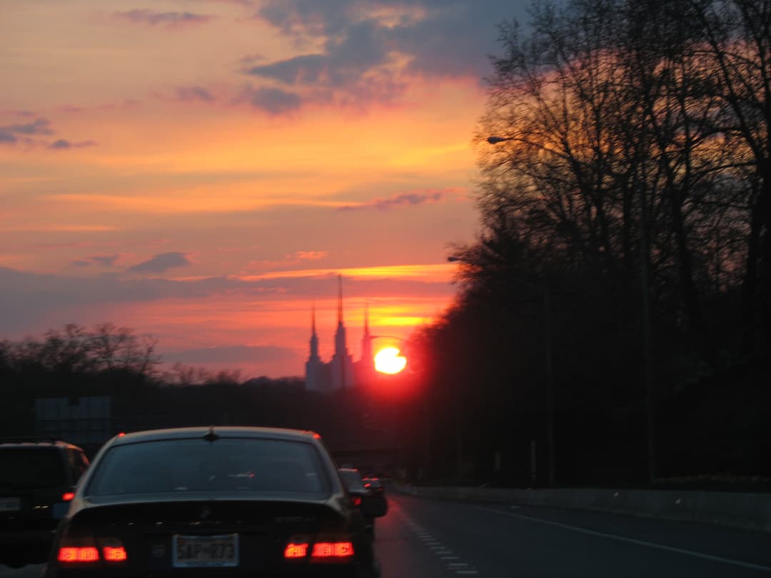 Washington D.C. Temple's six spires silhouetted at sunset from a road.