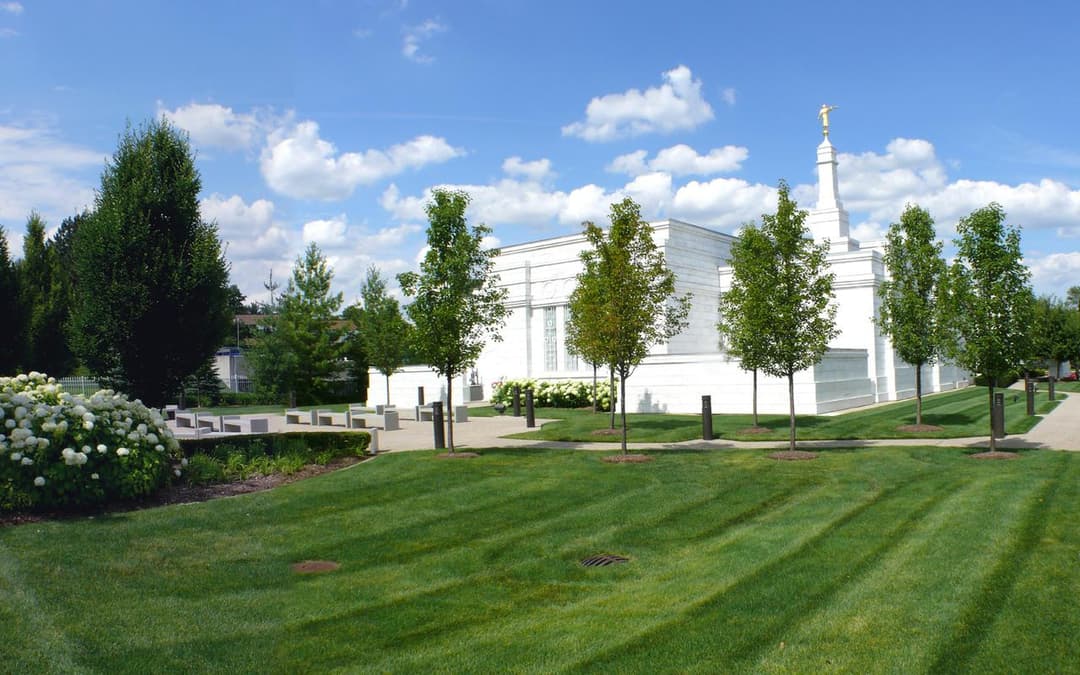 Detroit Michigan Temple exterior, Moroni statue, manicured lawn, sunny day.