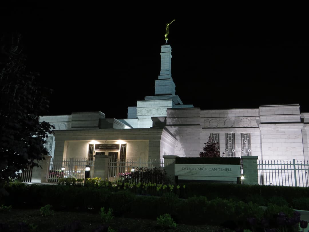 Detroit Michigan Temple exterior at night, with Angel Moroni and gardens.