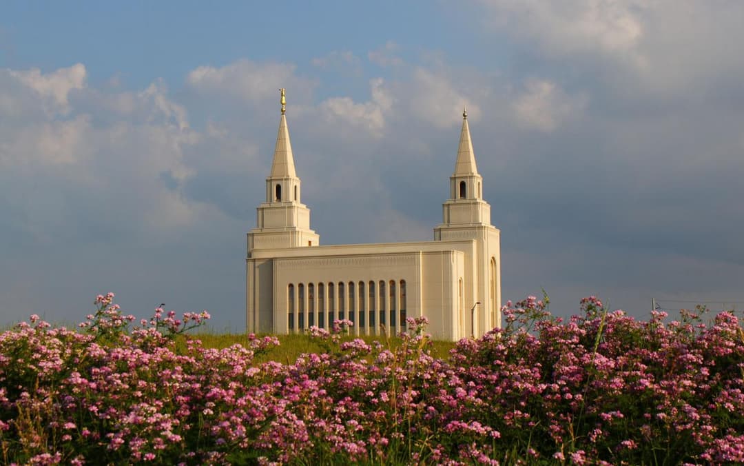 Kansas City Missouri Temple with two spires, framed by pink flowers.