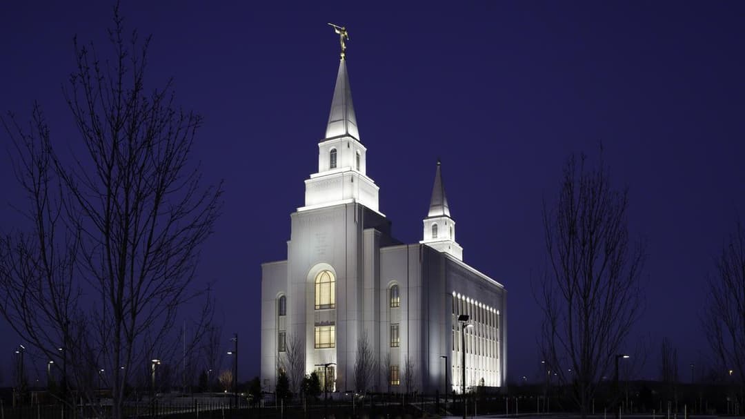Kansas City Missouri Temple at night, illuminated, with two spires and Moroni.