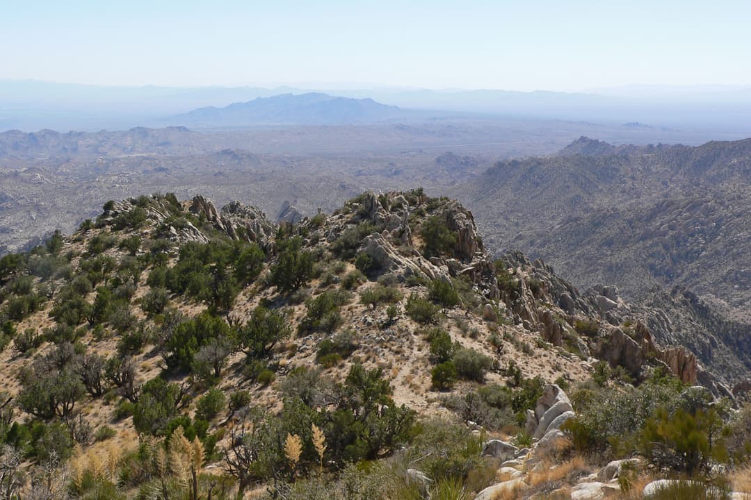 High-angle wide view across rocky ridges toward the distant desert valley.