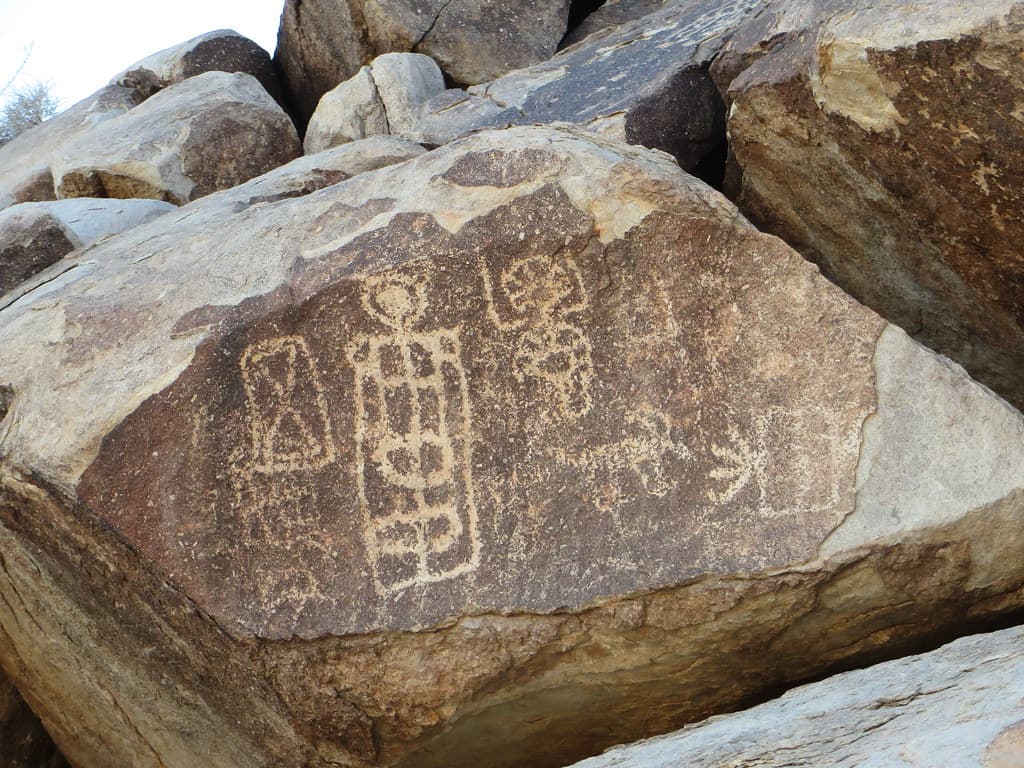 Ancient petroglyphs carved into a desert-varnished granite boulder.