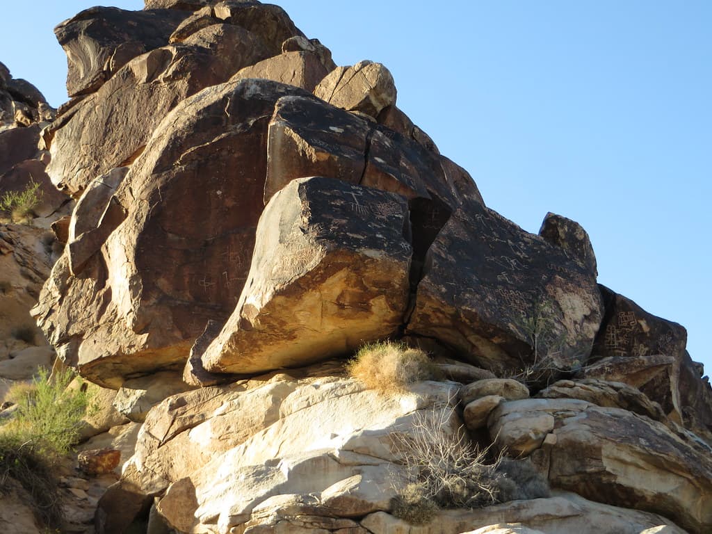 Sunlit petroglyphs etched on dark-varnished rock in Grapevine Canyon.