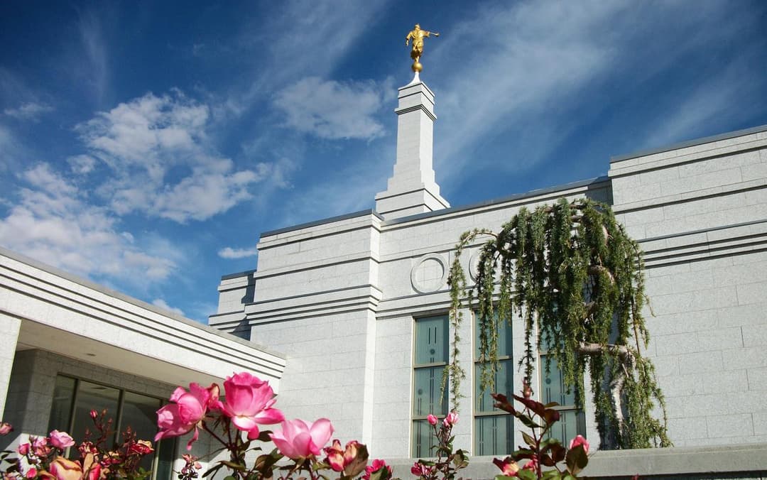 Low-angle view of the Reno Nevada Temple spire framed by pink roses.