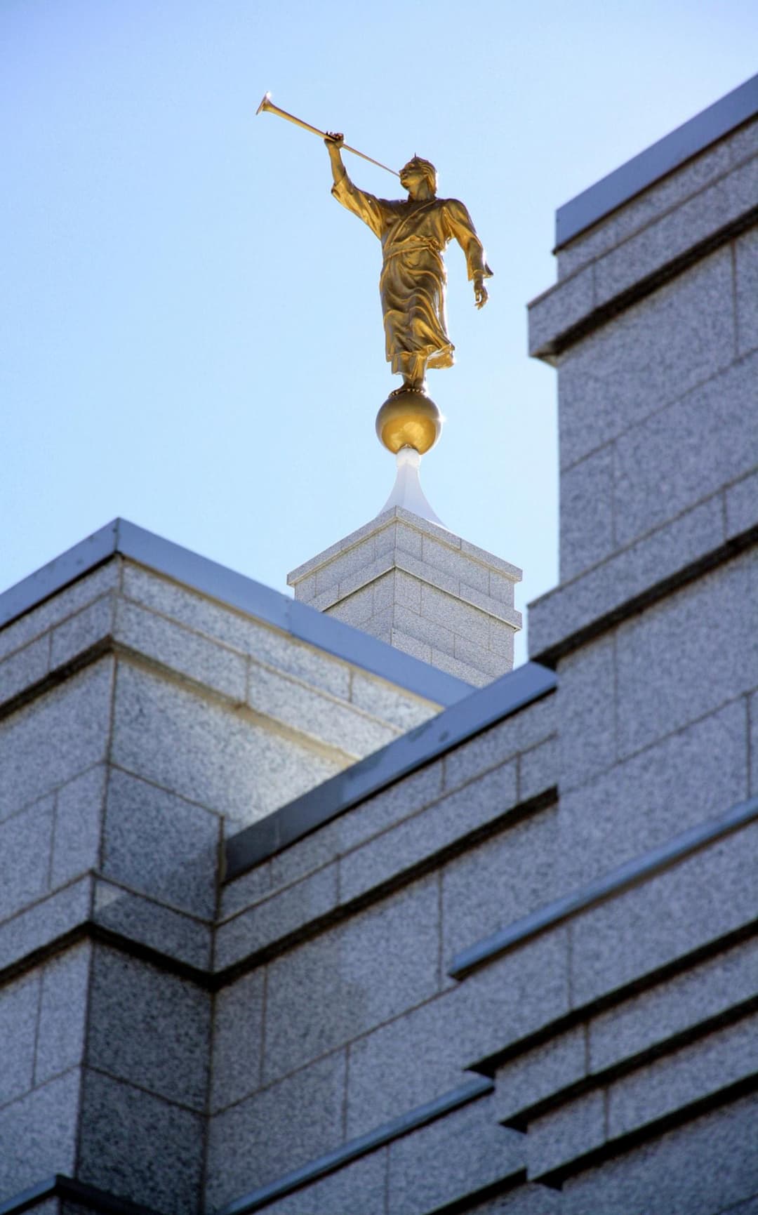 Low-angle view of the golden Angel Moroni statue atop the granite spire.