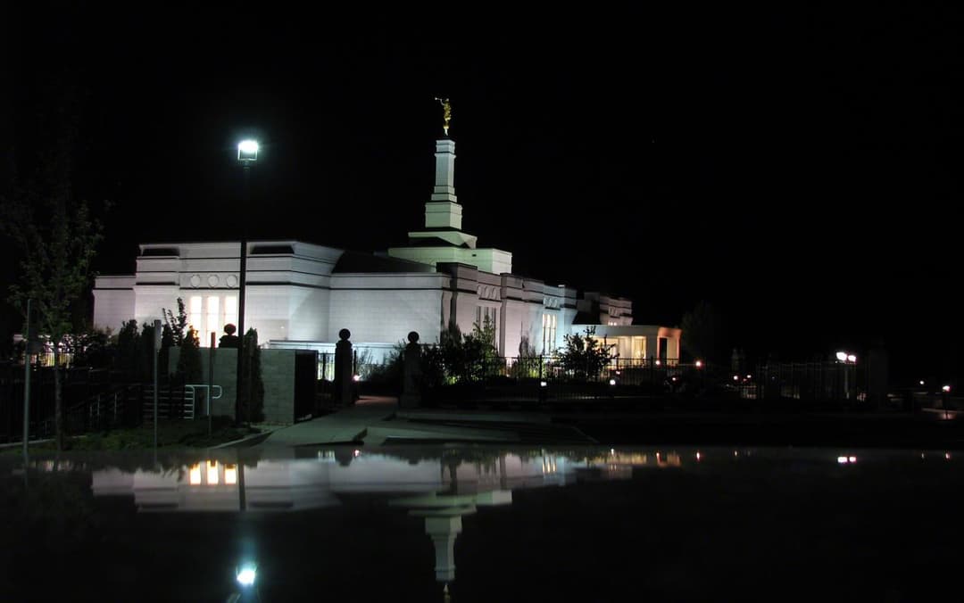 Night view of the illuminated Reno Nevada Temple reflected in water.