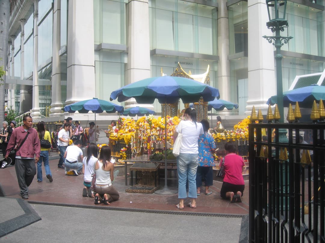 Worshippers praying before the flower-adorned Phra Phrom shrine.