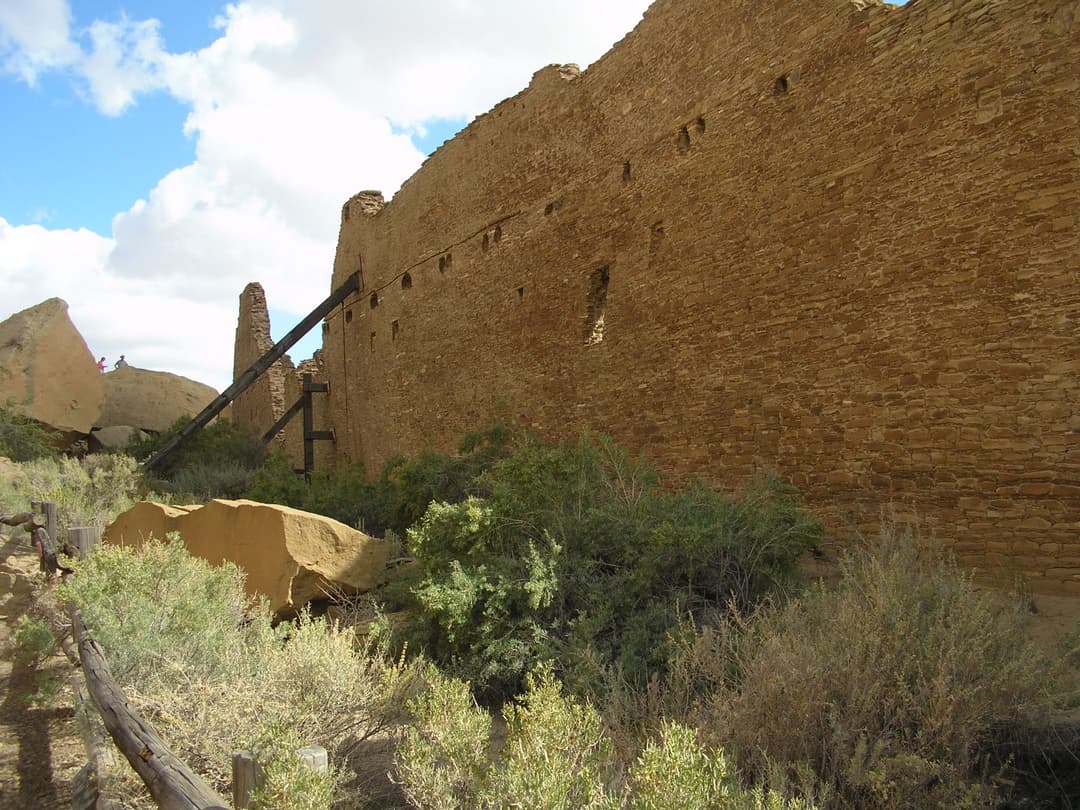 Exterior view of Pueblo Bonito's massive sandstone wall with wooden shoring.