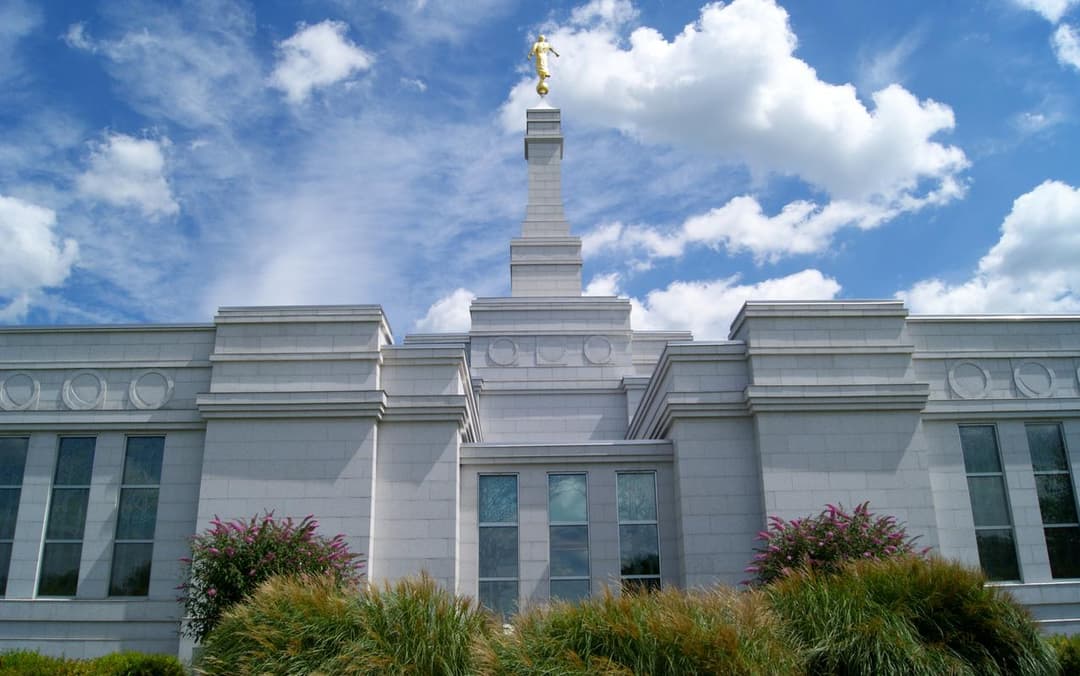 Exterior del Templo de Palmyra Nueva York, ángulo bajo, con el Ángel Moroni y nubes.