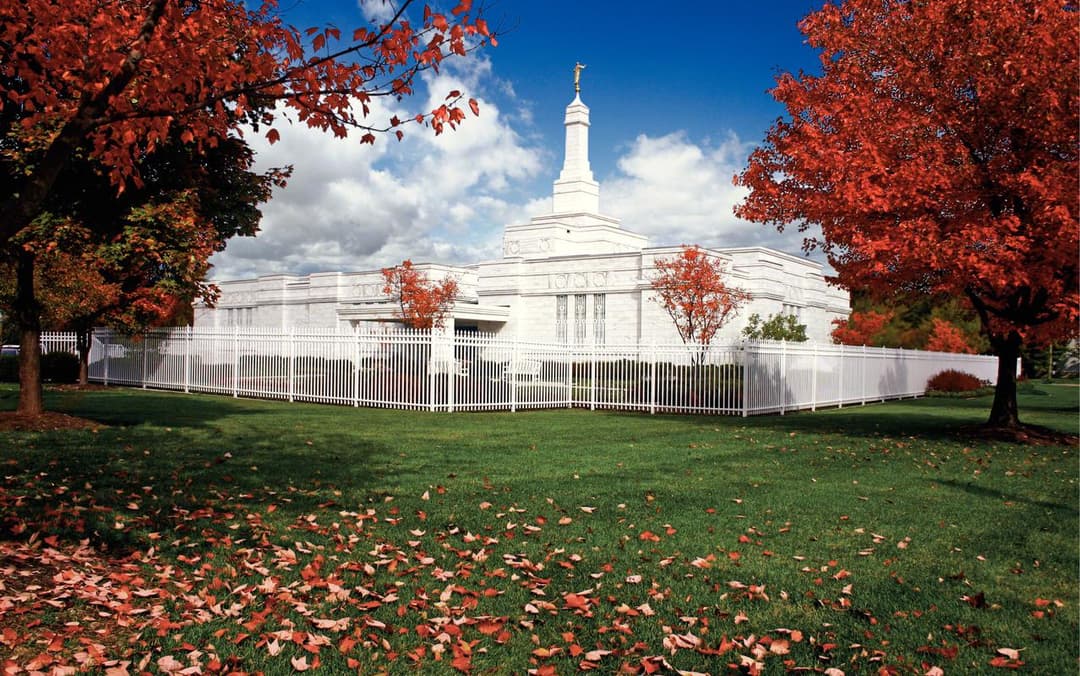 Autumn view of the Columbus Ohio Temple framed by vibrant red trees.