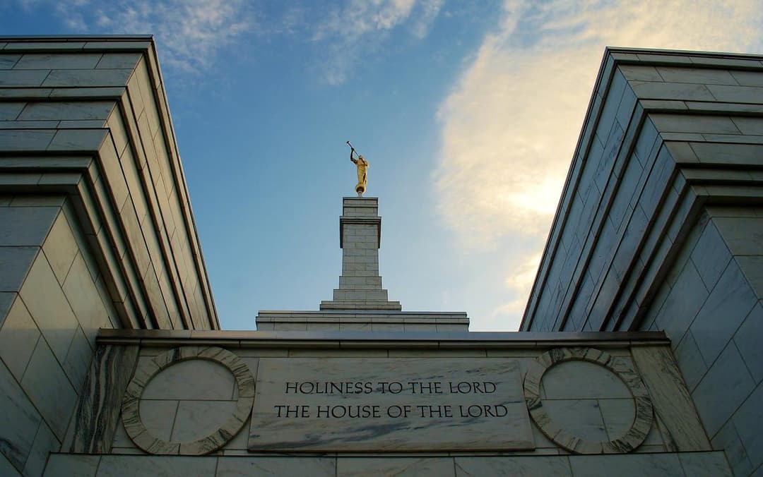 Low-angle view of the temple inscription and spire in late afternoon.