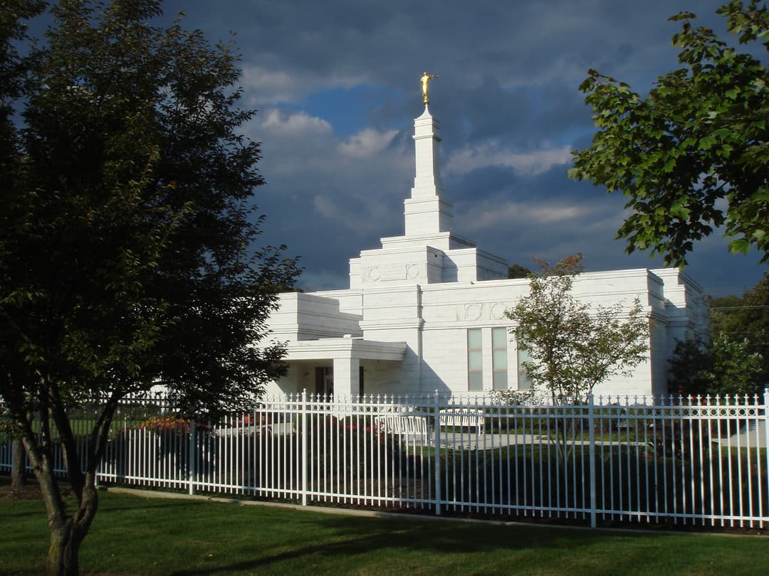 Sunlit Columbus Ohio Temple exterior against a dramatic, dark sky.