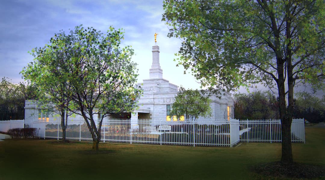 The Columbus Ohio Temple at twilight, framed by trees.