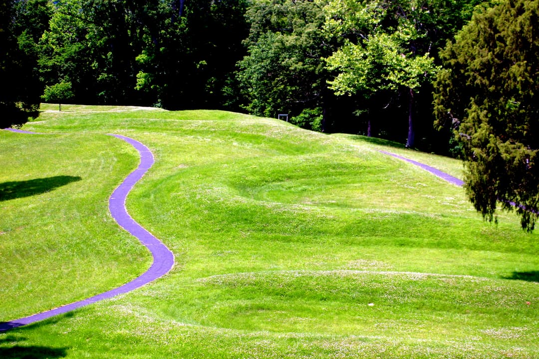 Grounds view of the undulating serpent earthwork coils and paved path.