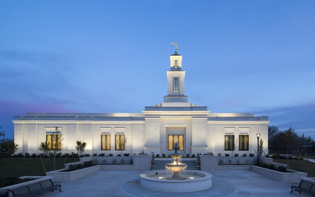 Oklahoma City Oklahoma Temple at twilight, featuring its spire and fountain.