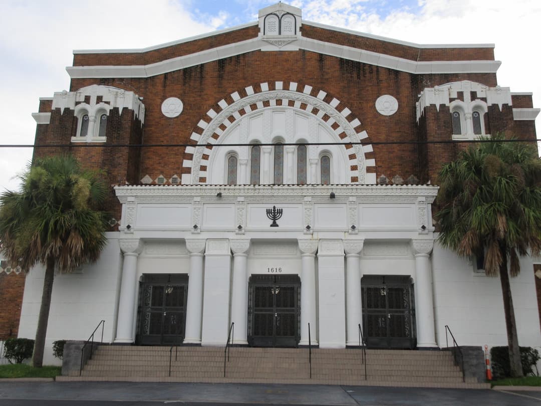 Frontal view of the main entrance facade flanked by palm trees