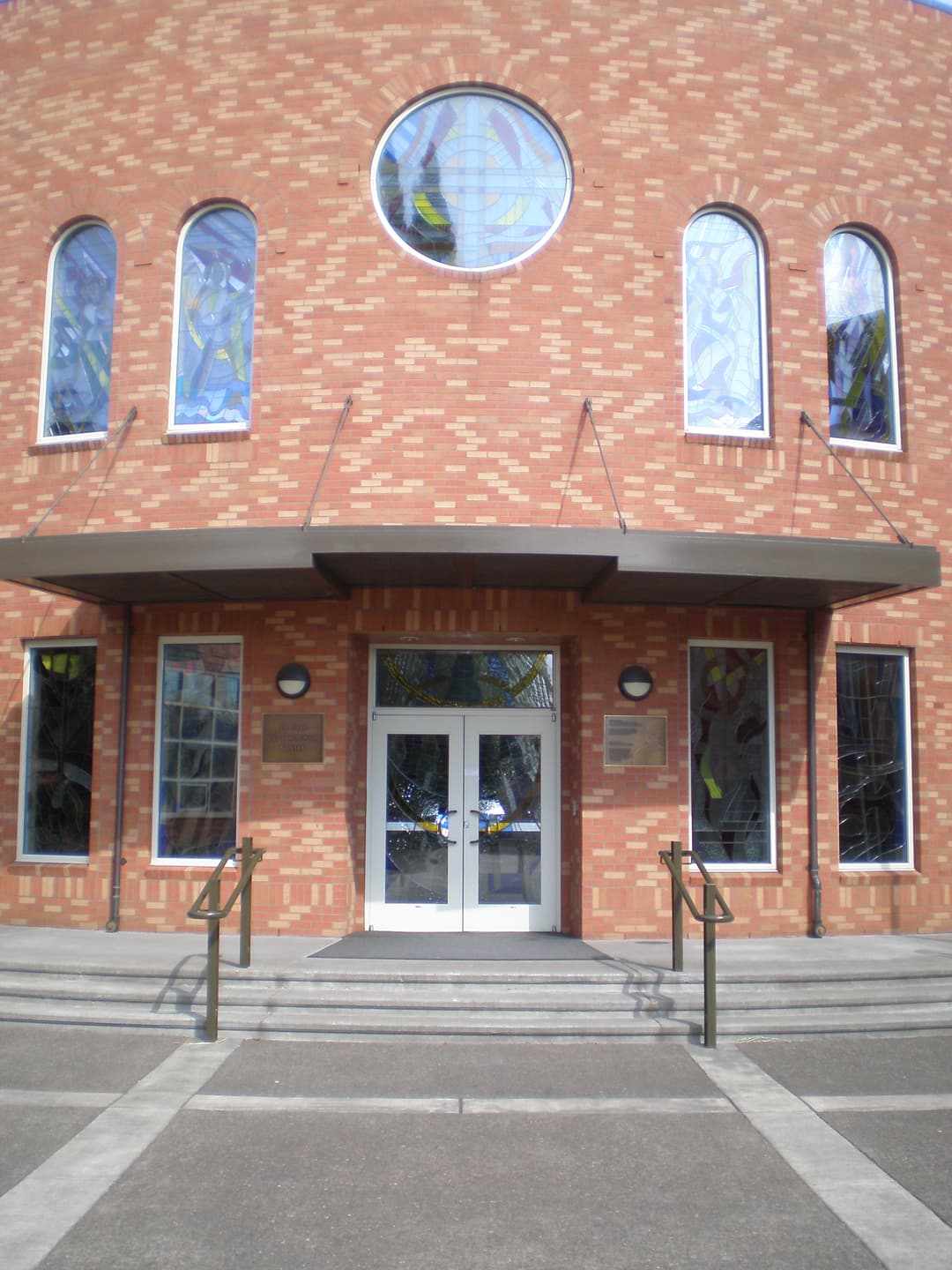 Brick entrance facade featuring stained-glass windows and canopy