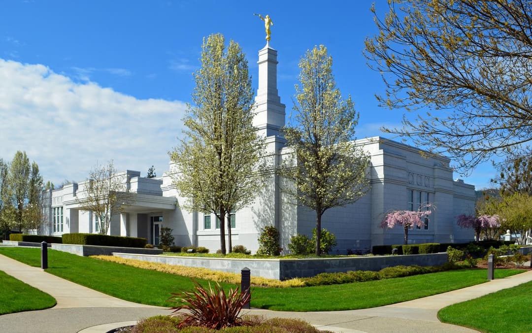 Medford Oregon Temple exterior with Angel Moroni and blooming trees.