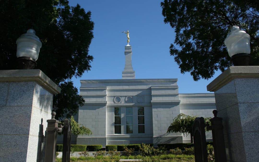 Medford Oregon Temple with Angel Moroni, framed by gate pillars.