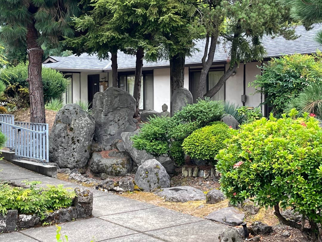 Japanese rock garden with stone Buddha statue on temple grounds.