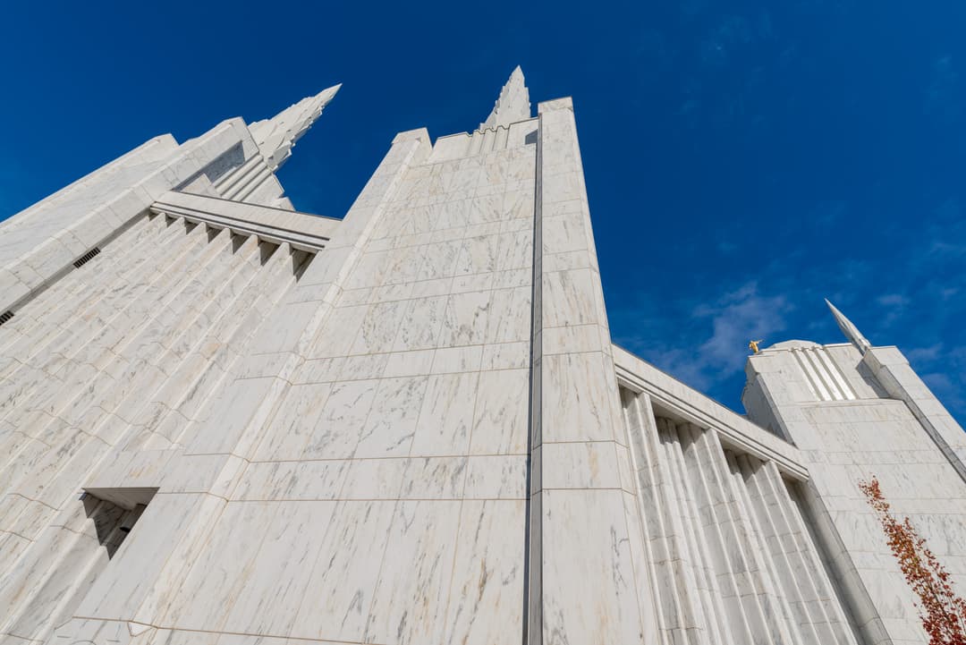Upward view of the Portland Oregon Temple's white marble facade and spires.