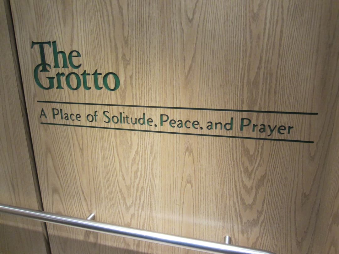 Wooden panel reading "The Grotto: A Place of Solitude, Peace, and Prayer.