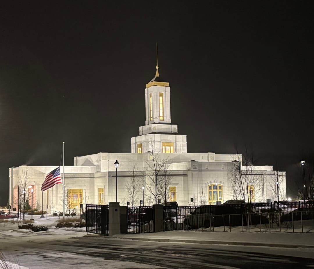 Exterior view of the illuminated temple at night with snow on the ground.