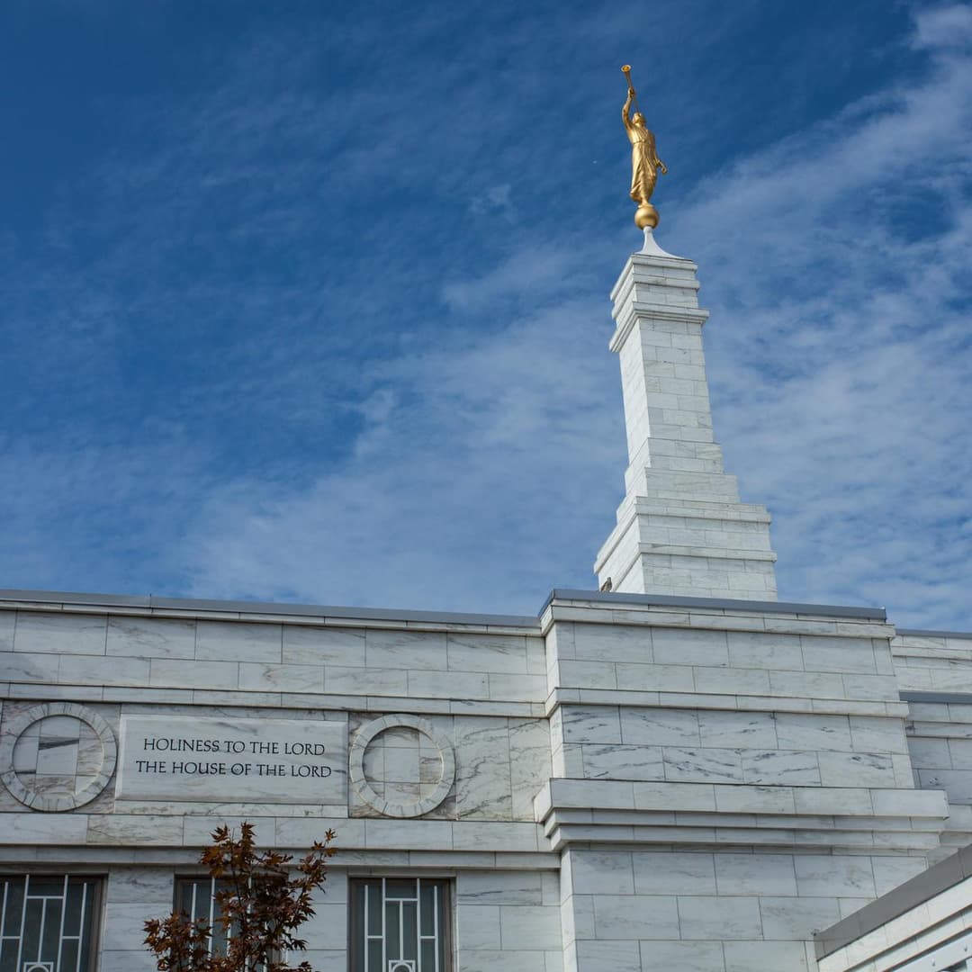 Low-angle detail of the temple spire, Angel Moroni, and inscription.
