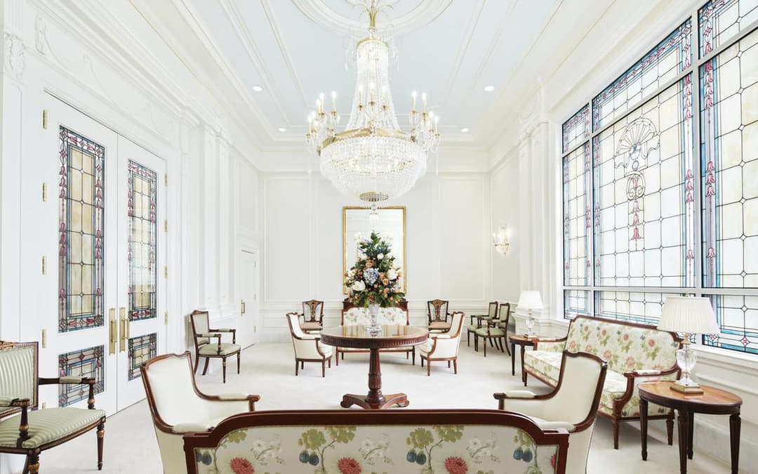 Elegant interior room with chandelier, stained glass, and ornate furniture.