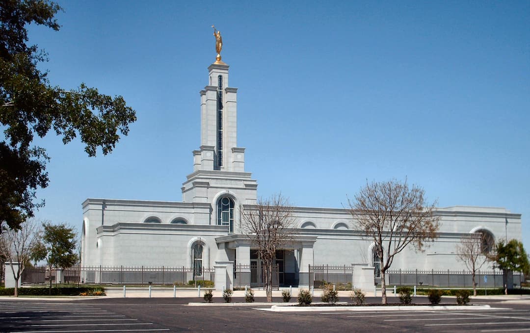 Wide view of McAllen Texas Temple, Angel Moroni, trees, and parking lot.